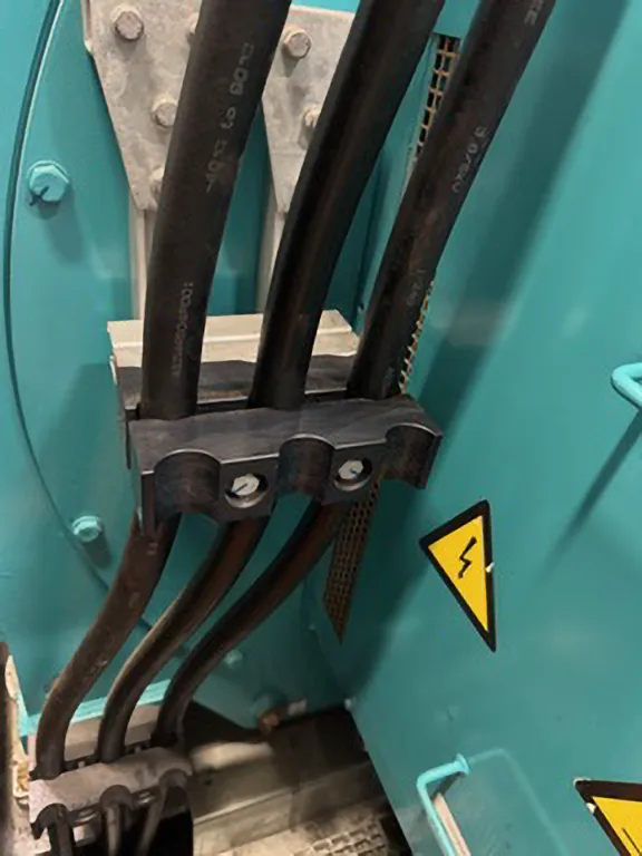 Close-up of ïd-Technik cable clamps holding multiple MV power cables in place within a high-voltage electrical enclosure.